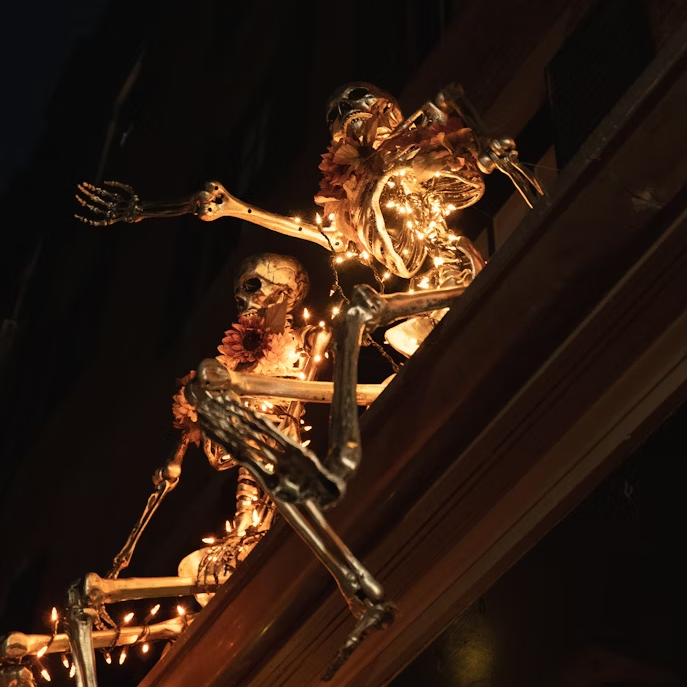 skeletons-are-climbing-a-building-decorated-with-lights