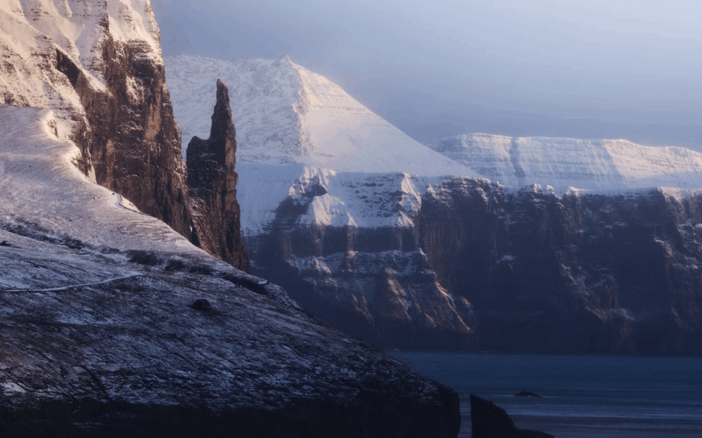 10 stunning Facts Why Faroe Islands Are a Dream Photo Spot 9 a-snow-covered-mountain-with-a-body-of-water-in-the-foreground