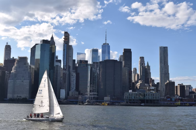 Where’s the Best Place to Sail for Beginners in the USA? 19 A sailboat in a body of water with a city in the background