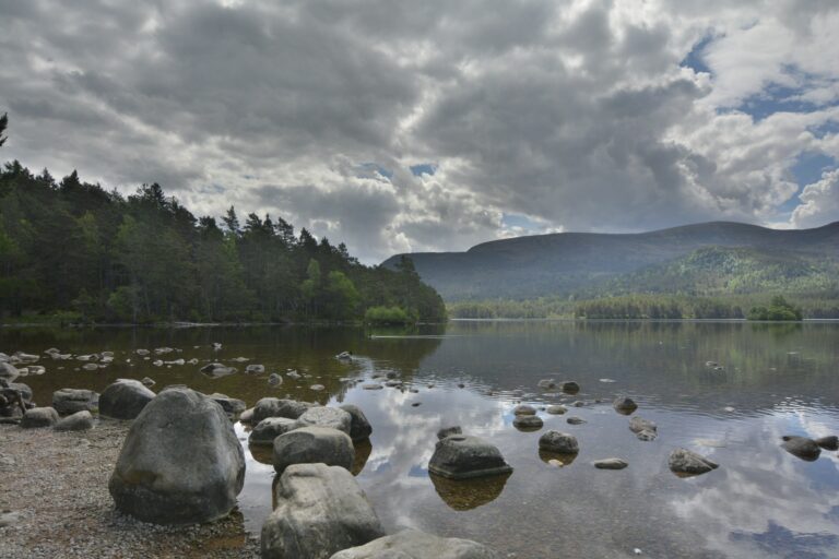 This Hidden Scottish Loch Looks Too Perfect to Be Real — Here's How to Visit Loch an Eilein 11 Loch an Eilein, a hidden Scottish loch surrounded by forest, with crystal-clear water reflecting the sky and nearby mountains