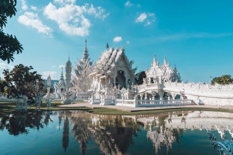 Chiang Rai White Temple sitting next to a body of water in daytime